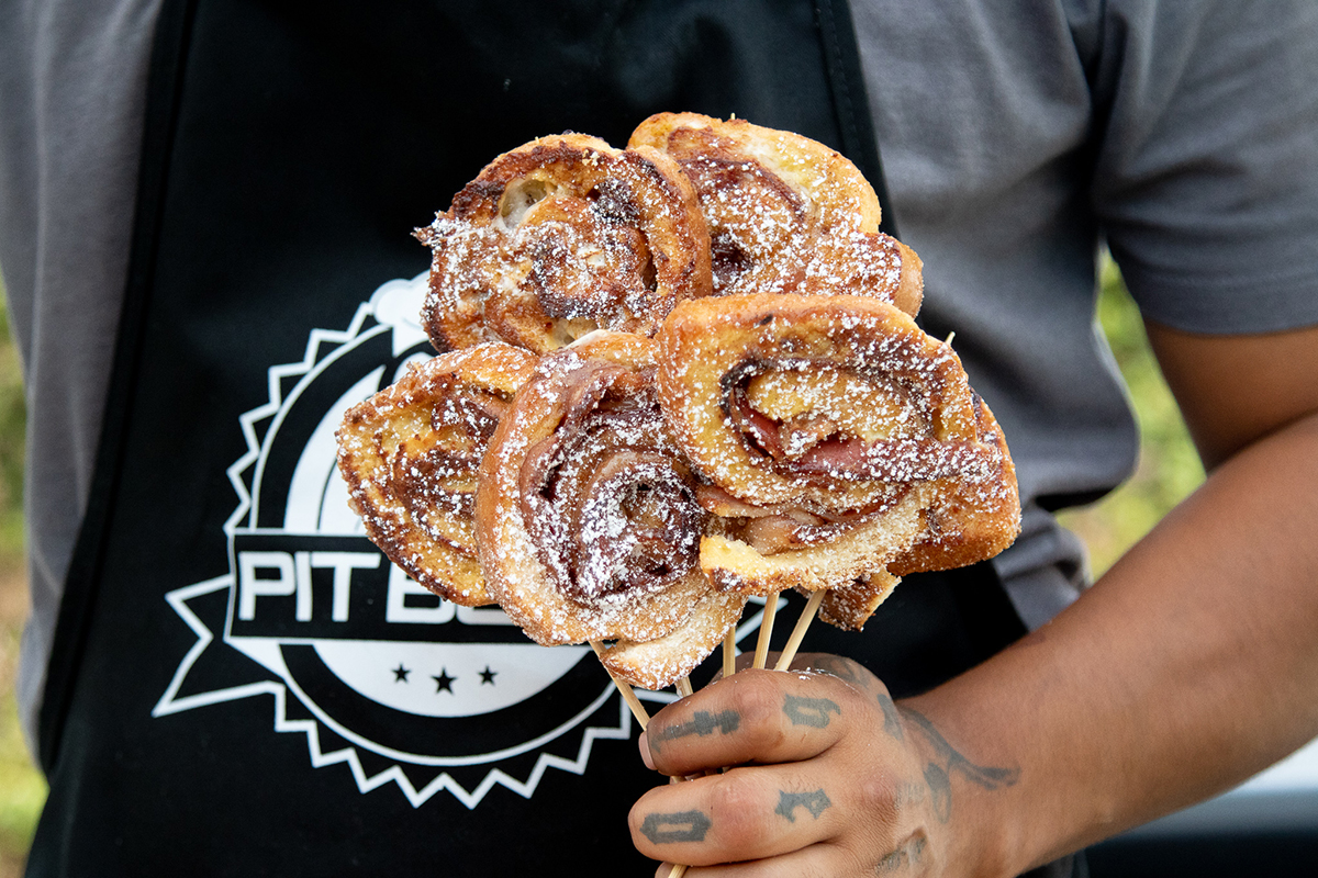 Yummy cinnamon pinwheels with powdered sugar on a wooden skewer