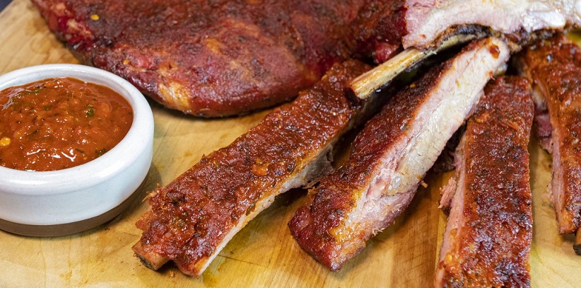 cooked and separated ribs next to bowl of sauce