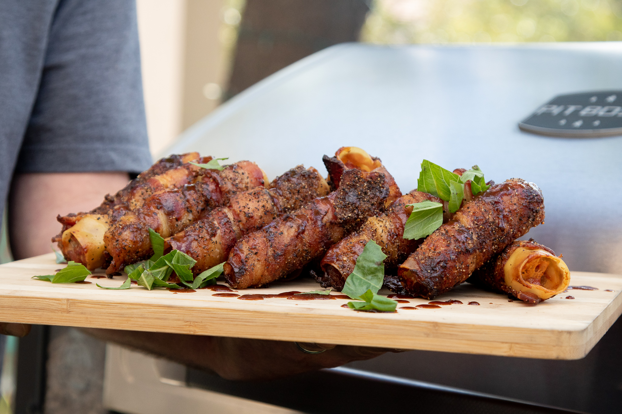 sausage-stuffed pasta shells wrapped in bacon smoked on Pit Boss grill and plated on wooden cutting board