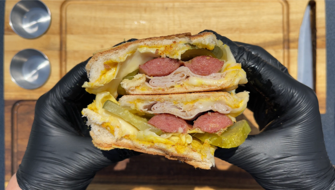 hot dog sandwich sliced in half over wooden cutting board